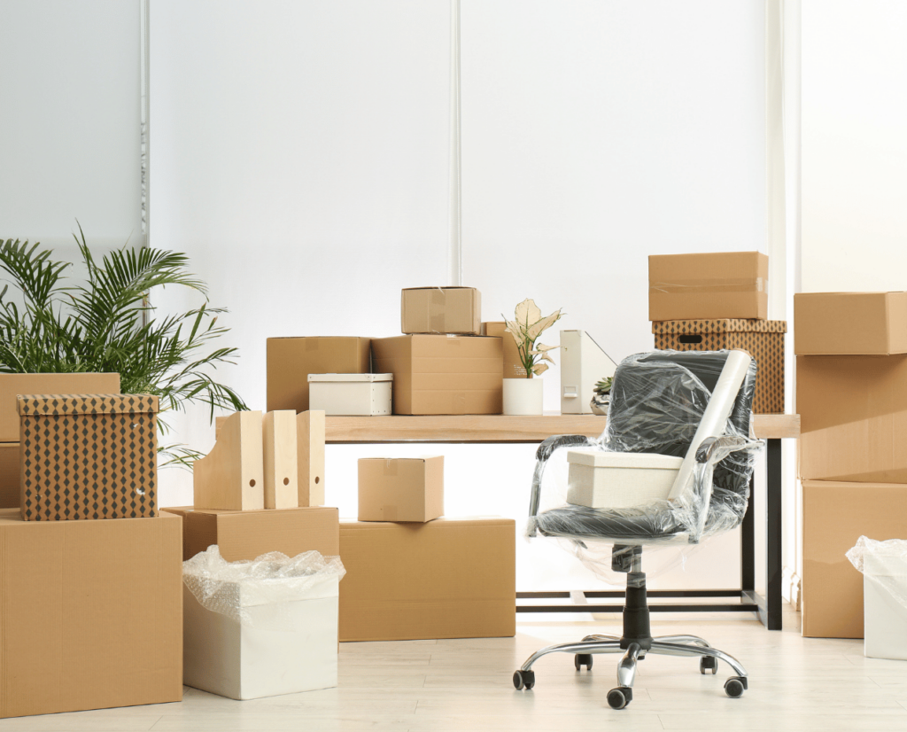 Bureau professionnel empaqueté dans divers cartons avec chaise de bureau protégée pour déménagement.